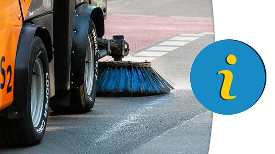 Eine Straßenkehrmaschine reinigt mit rotierender Bürste die Fahrbahn am Straßenrand, während ein Hinweis-Symbol auf wichtige Informationen aufmerksam macht.