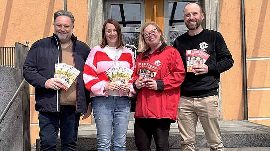 Vertreterinnen und Vertreter der Agentur für Haushaltshilfe präsentieren gemeinsam vor dem Rathaus Informationsflyer zu ihrem Unterstützungsangebot.