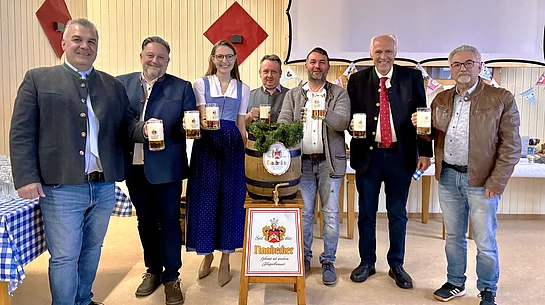 Mehrere Vertreter und Organisatoren stehen gemeinsam um ein Bierfass der Brauerei Naabecker und halten gefüllte Bierkrüge in die Kamera.