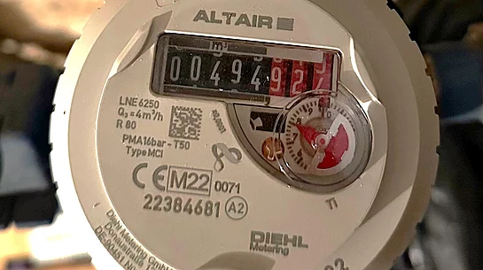 Nahaufnahme eines Wasserzählers, dessen Ziffernstand deutlich ablesbar ist und von technischen Angaben auf dem Gehäuse umgeben wird.