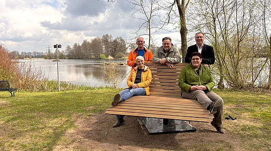 Mehrere Beteiligte präsentieren am Ufer des Hütwirls in Münchshofen eine neue Panorama-Liege, die im Rahmen des Bürgerhaushalts aufgestellt wurde.