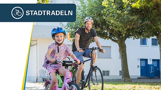 Ein Kind mit Fahrradhelm fährt auf einem kleinen pinkfarbenen Fahrrad voraus und lacht in die Kamera. Dahinter begleitet ein Erwachsener ebenfalls mit Fahrradhelm das Kind auf einem größeren Fahrrad. Die beiden fahren bei sonnigem Wetter auf einem Weg an Bäumen und Gebäuden vorbei. Oben links ist das Logo der Aktion „STADTRADELN“ eingeblendet.